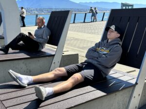 Teen stretched out on bench next to Vancouver lake